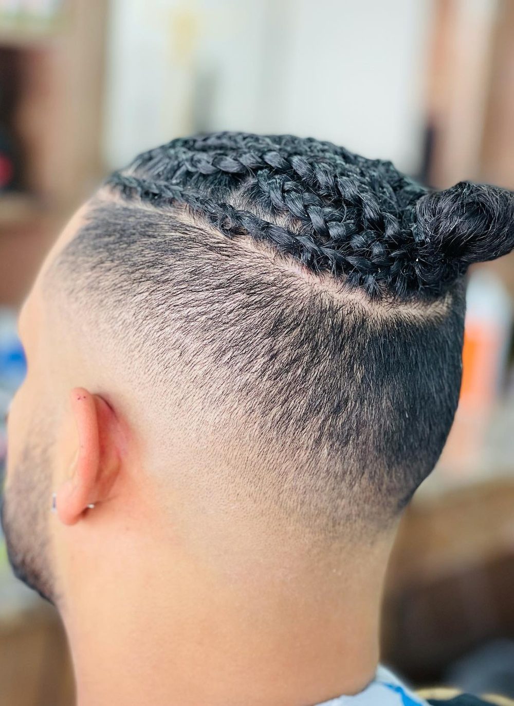 Braids gathered on top with a skin fade cut through the sides and round the back.