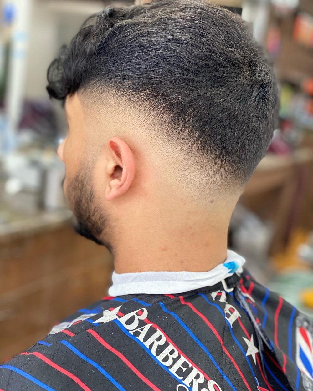 Curly hair left long on top with the back and sides tapered in underneath it.