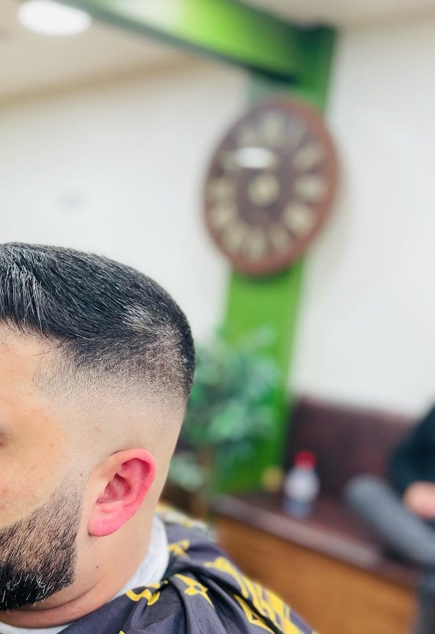 A dark fade blended above the ear, with the beard lined up and joined into it.