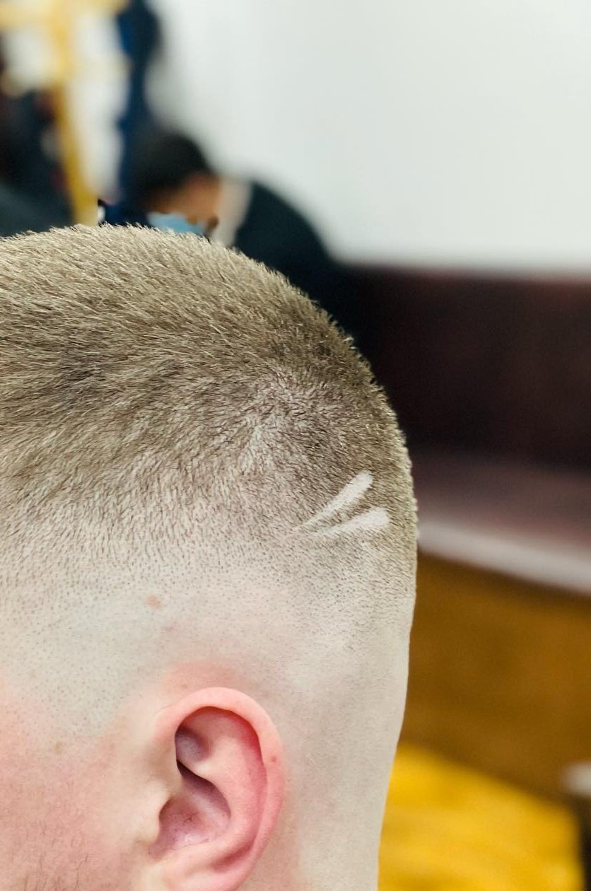 A short skin fade with a shaved line cut into the side, graded down to the skin above the ear.